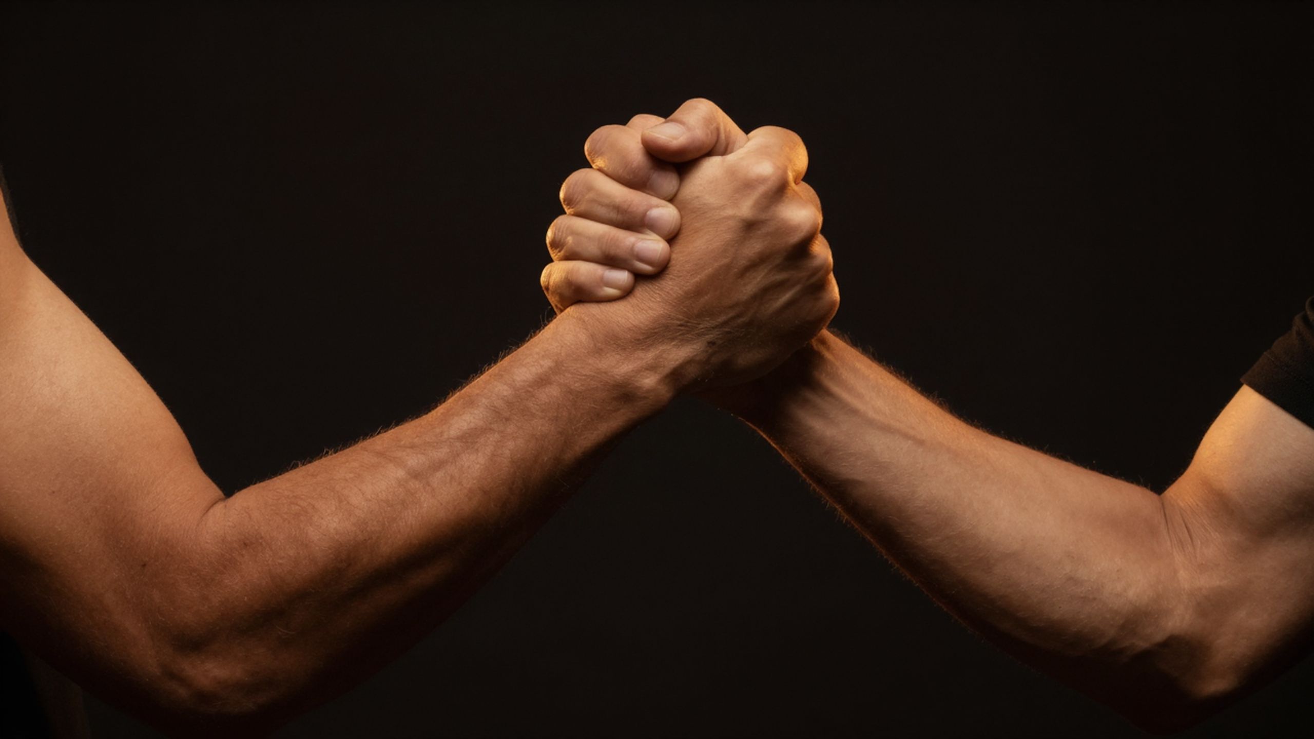 Als Symbolbild für dir Körperarbeit mit Männern eine Nahaufnahme zweier Männer, die sich einen Handschlag geben.