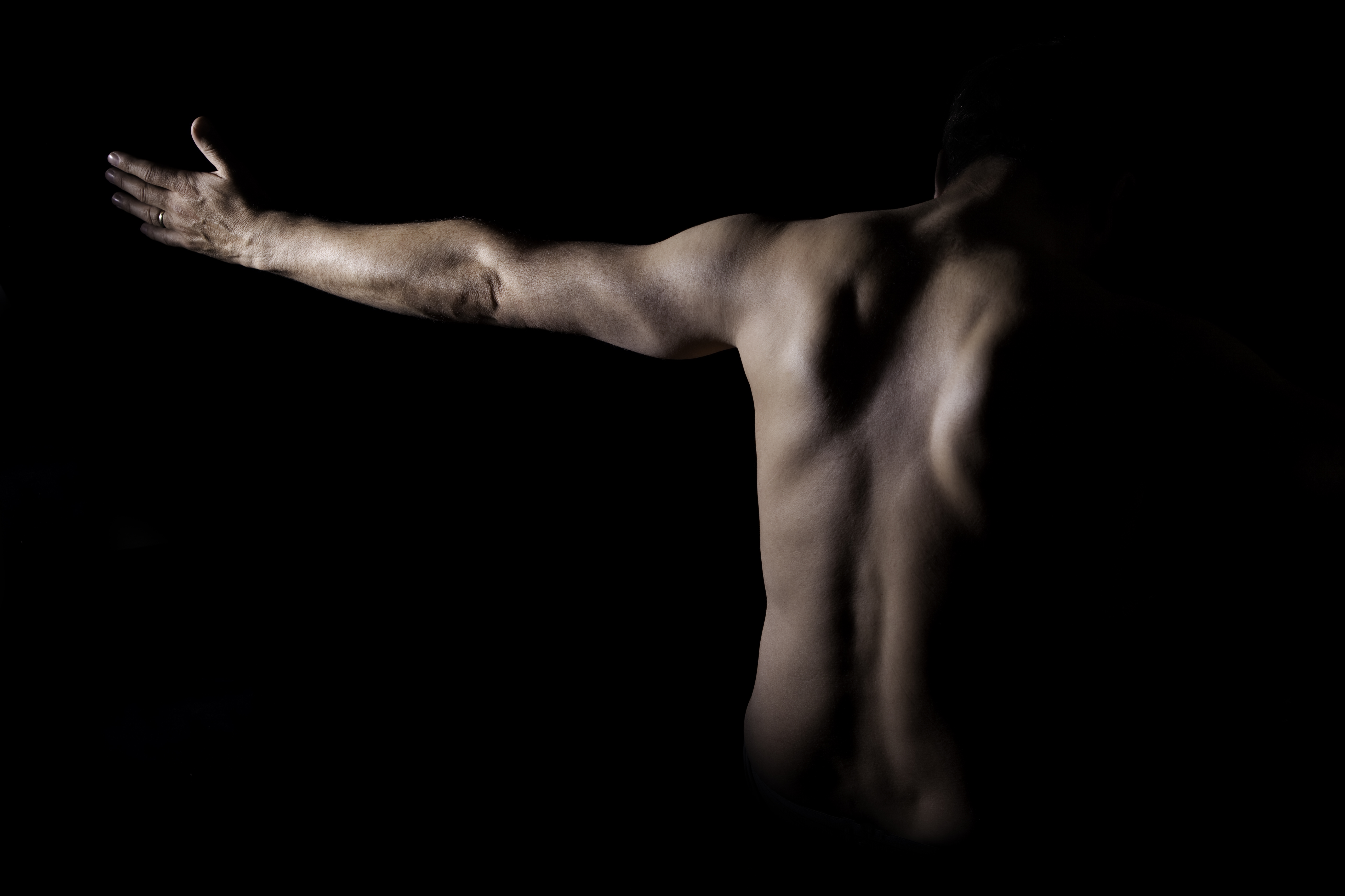 Rückenansicht eines Tantra interessierten Mannes mit ausgestrecktem Arm.