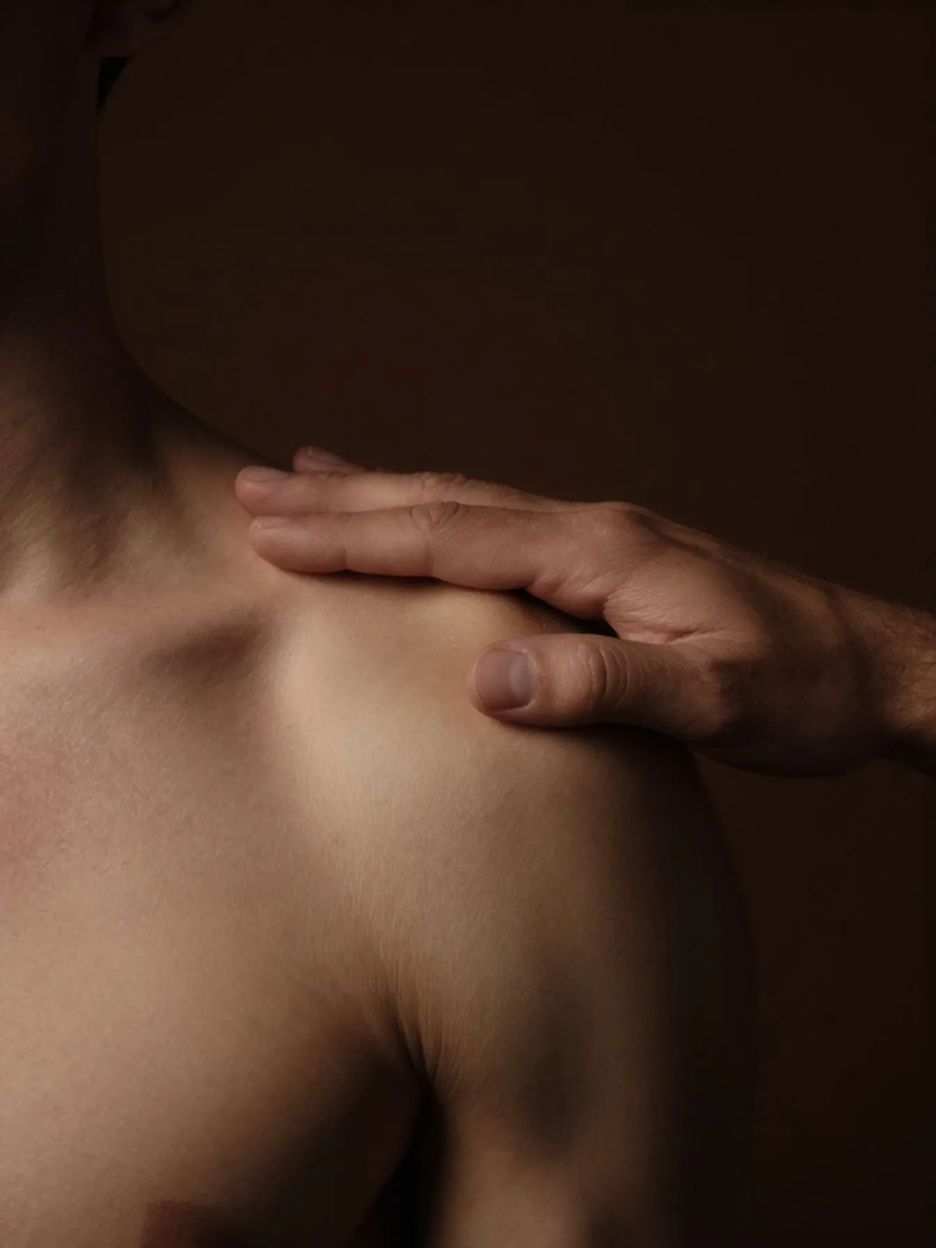 Ein Mann legt seine Hand achtsam auf die Schulter eines anderen Mannes innerhalb einer tantrischen Begegnung.